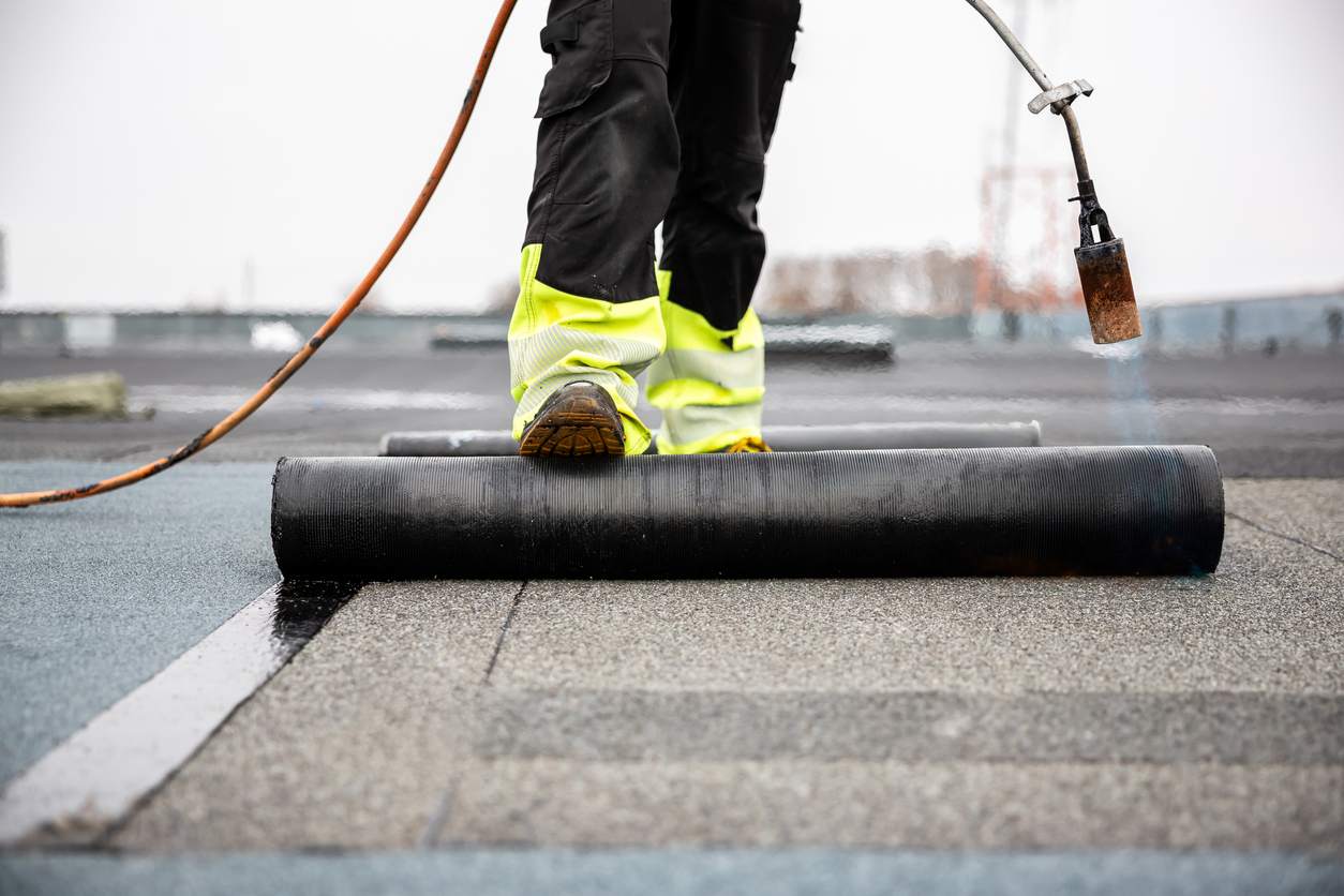 A foot rolling asphalt roofing out