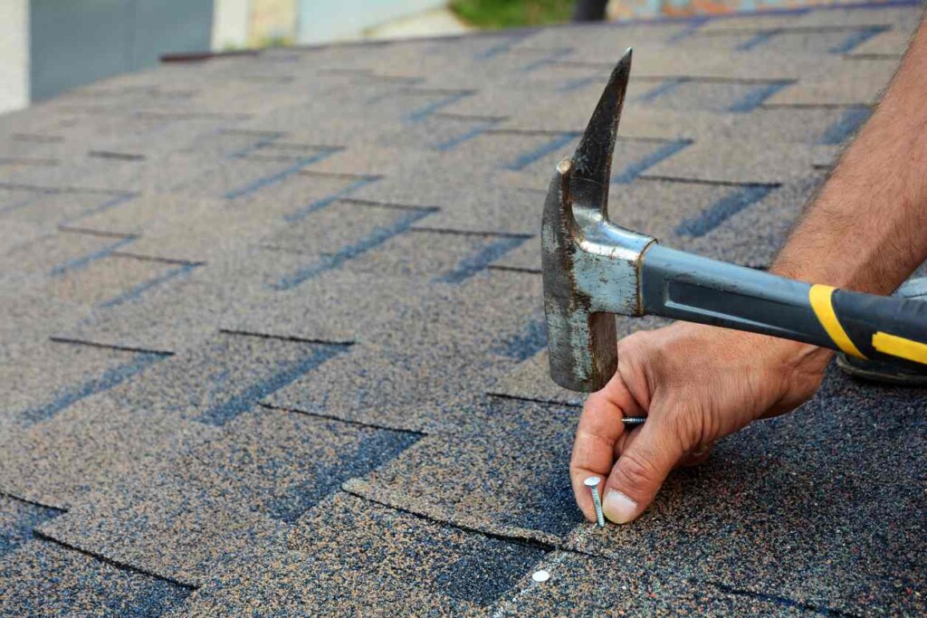 A hammer hitting in the final nail on a composition shingle roof